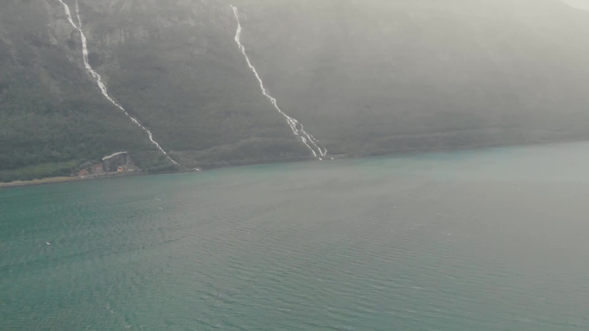 Aerial drone flight over a fogy scenery. A lake and a rock behing. North European landscape