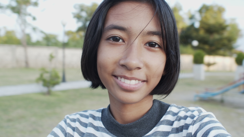 Asian girl little is playing a carousel at the park. Asia girl kid Wearing a black and white striped shirt