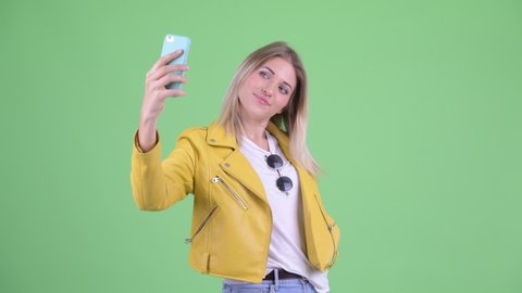 Happy young rebellious blonde woman taking selfie