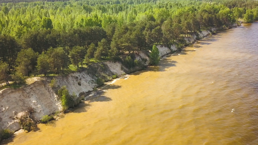 4K  Aerial. Fly  over coastline with dirt water and wood. Diagonal composition 