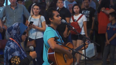 Kuala Lumpur, Malaysia - March 25th, 2019 : Group of blind community performing busking, street musician, crowds of people listening to the music at sidewalk of Bukit Bintang at night.