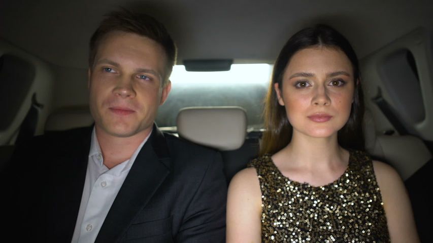 Smiling celebrities sitting on back seats and looking at camera, superstars