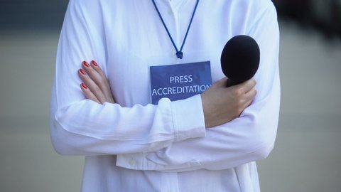 Woman with microphone and press accreditation badge, media pass for journalist