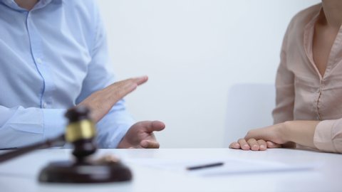 Spouses arguing about property division during divorce, gavel and rings closeup