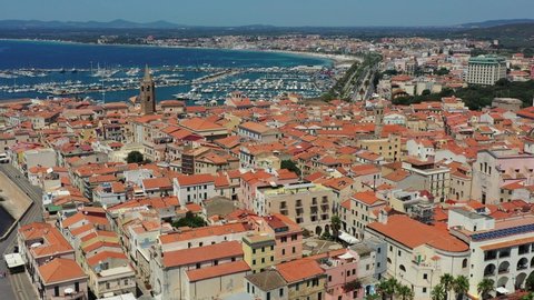 Aerial shot over Alghero old town, cityscape view on a beautiful day with harbor and open sea in view. Alghero, Italy. Panoramic aerial view of Alghero, Sardinia, Italy. 