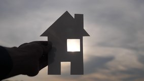 happy family construction house concept. man holding home a paper house in his hands at sunset silhouette sunlight. life ecology lifestyle video symbol