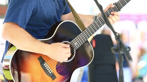 Close Up of Man Playing Acoustic Guitar Outdoors - Shallow Depth of Field.