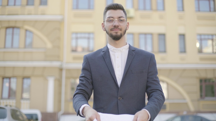 Attractive and confident young businessman in an official suit threw out business papers after the deal