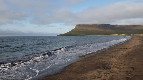 dollyshot of waves gently splashing on the dark sand on the beach in Snaefellsnes, Iceland