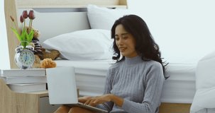 Portrait scene video of beautiful Asian woman in pajamas using notebook computer, concept for working on bedroom.
