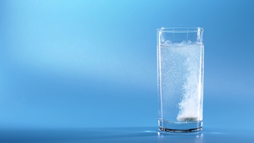 Effervescent Tablet Falling In Water. Pill Falls And Dissolves With Bubbles. Effervescent Tablet In Glass Of Water On Blue Background. Shot Of Effervescent Pill Dissolving In A Glass Of Water. | Shutterstock HD Video #1035968216