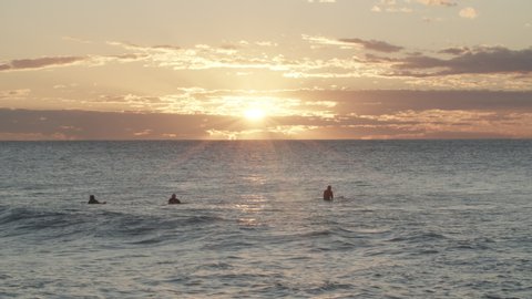 Surfers sitting waiting for waves in ocean sunrise 4K