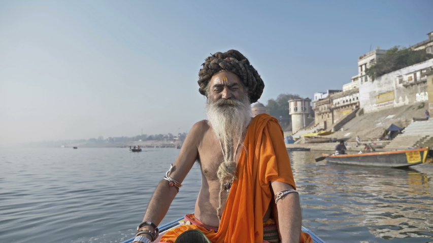 A bearded Sadhu sitting on a boat in the river ganges. He is wearing a bracelet made of rudraksha beads in both hands,Varanasi, India. (March 2019) Royalty-Free Stock Footage #1035979625