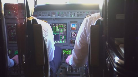 view from the cockpit of an airline operating a luxury private jet during the day, a commercial pilot on a charter flight, a landing plane, two pilots board a plane, rear view. Devices. 