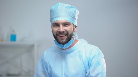 Smiling surgeon taking off medical face mask after successful operation, work