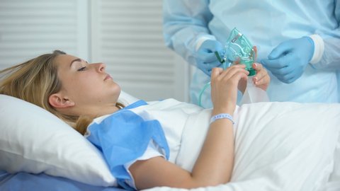 Nurse wearing female patient oxygen mask, preparation before surgery, hospital