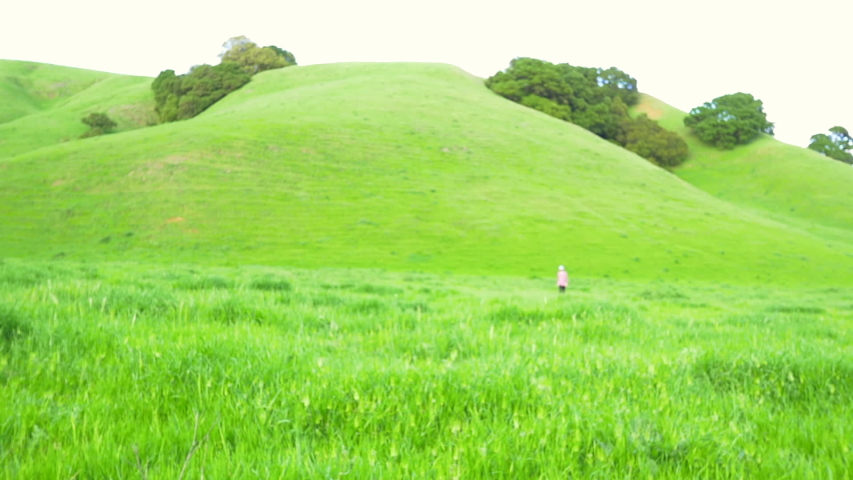 Boy running through tall grass in green field