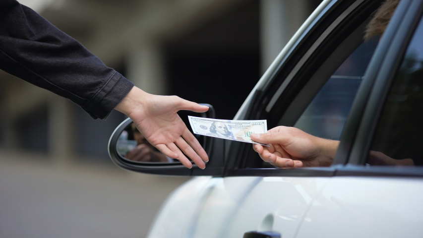 Driver opening car window and paying hundred dollars for international highway | Shutterstock HD Video #1035991568