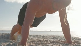 Video of fit shirtless man doing arm exercises on the beach at sunrise