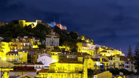 Lisbon, Portugal. Aerial view of Lisbon, Portugal at night with view over old Alfama and fortress. Time-lapse with dark cloudy sky, panning video