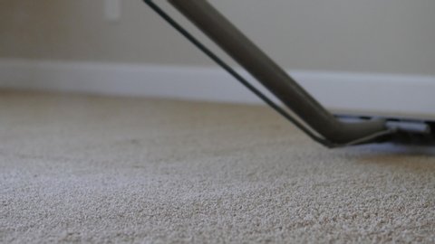 carpet cleaner sprays out a big poof of steam on tan carpet being cleaned. Steam cleaning machine lets out large poof of steam as it is used on tan carpet.