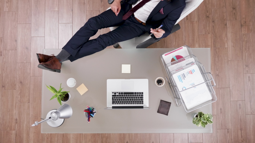 Top view of businessman in suit staying relaxed with feet on his office desk. Modern looking office. | Shutterstock HD Video #1036001363