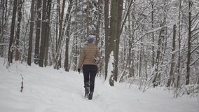 Video of young woman in woolen hat going skiing in snowy forest