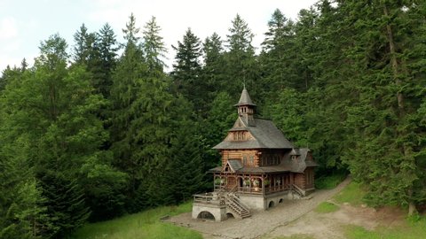 Drone shot at an old wooden church in a coniferous forest. Suburb of Zakopane in Poland.