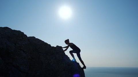 Young woman walks uphill towards the summit in Slow motion. Silhouette of a Lady hiking in beautiful Crimean mountains.