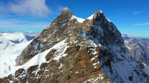 Aerial, drone shot, towards snowy, Jungfrau mountain ridge, at Jungfraujoch, the top of Europe, on a sunny, day, in Bernese Alps of Switzerland