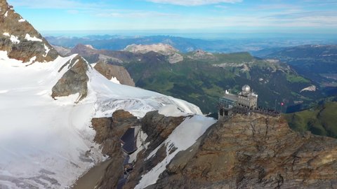 Aerial, drone shot, panning around the Sphinx Observatory, at Jungfraujoch, the top of Europe, overlooking alpine mountains of the Bernese Alps, on a sunny day, in Switzerland