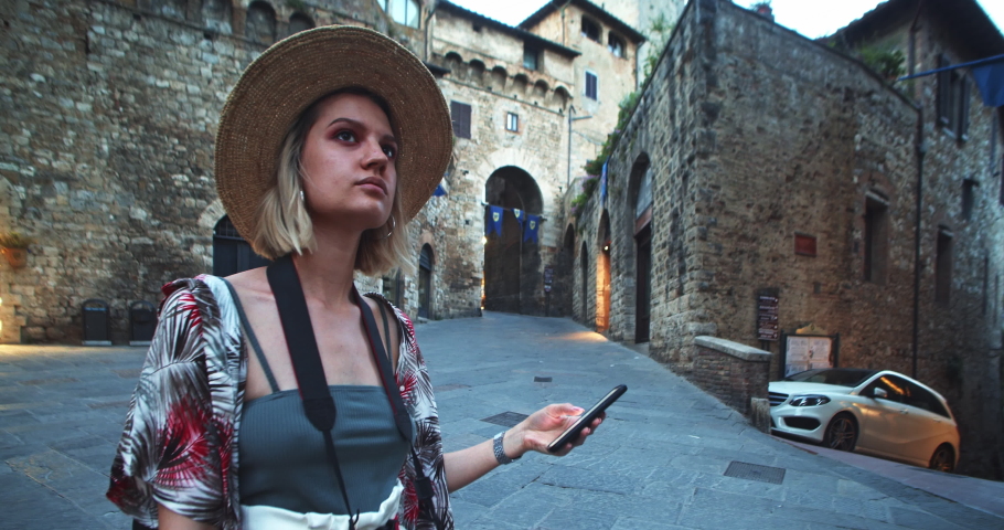 Augmented reality of digital point map searching app. Young tourist girl uses futuristic navigator on modern smartphone in hystorical old city. Animation of destination location. Future technology