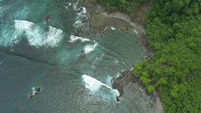 Aerial Drone Video of waves hitting the shore of a tropical island with lush jungle