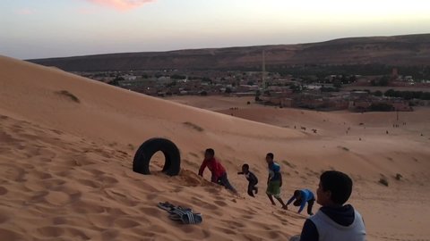 Taghit, Bechar, Algeria - November 03, 2017: Slow motion footage of playing children on dunes of Sahara Desert.