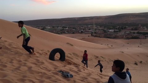 Taghit, Bechar, Algeria - November 03, 2017: Slow motion footage of playing children on dunes of Sahara Desert.