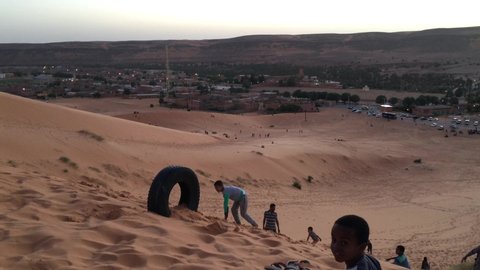 Taghit, Bechar, Algeria - November 03, 2017: Tuareg children are playing on dunes of Sahara Desert.