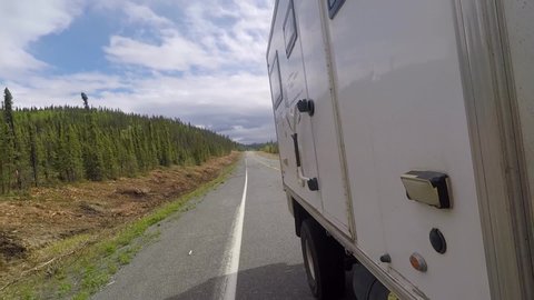 Rear view of 4x4 overland RV driving through frost heaves on the Alaska Highway.