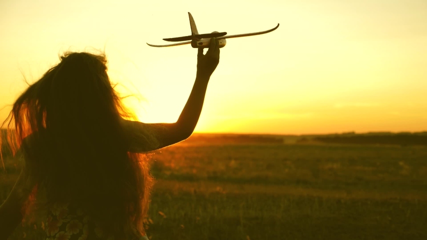 Happy girl runs with a toy airplane on a field in the sunset light. children play toy airplane. teenager dreams of flying and becoming a pilot. girl wants to become a pilot and astronaut. Slow motion Royalty-Free Stock Footage #1036020698