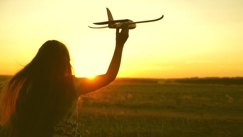 Happy girl runs with a toy airplane on a field in the sunset light. children play toy airplane. teenager dreams of flying and becoming a pilot. girl wants to become a pilot and astronaut. Slow motion | Shutterstock HD Video #1036020698