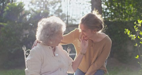 Granddaughter visiting,happy hugging grandmother at outside garden,backlight sun. Multigeneration women love holding together.White hair elderly grandma woman.Affection,togetherness,caring,loving