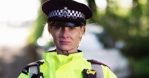 4K Close up portrait of serious female metropolitan police officer out on patrol. Slow motion.