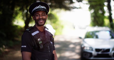 4K Portrait of smiling British police officer outdoors in scenic natural environment. Slow motion.