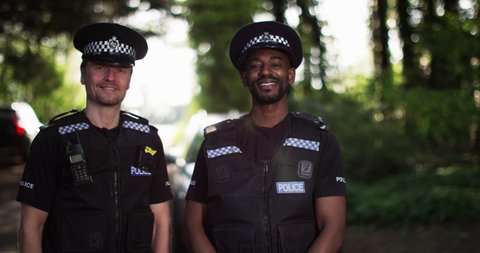 4K Portrait of smiling UK police officers on patrol in countryside area. Slow motion.