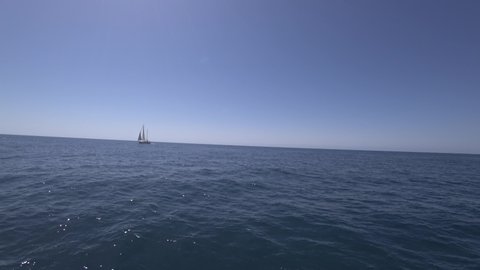 Sailing yacht on calm open sea during sunny summer day with bright sky