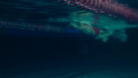 Amateur Swimmer Practicing in Water Swimming pool. Female swimmer practicing flip turn. Underwater view. Night shot. - Powered by Shutterstock - Get 15% off with code: PIKWIZARD15