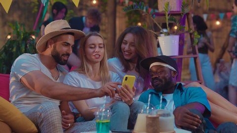 Group portrait of attractive positive friends chilling relaxing using mobile phone device having fun conversation on the party.