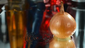 Onion that falls on the water and makes a splash. Slow motion video with black background, 4k