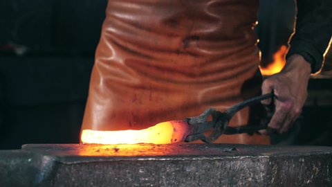 Incandescent metal element is getting forged. Slow motion.