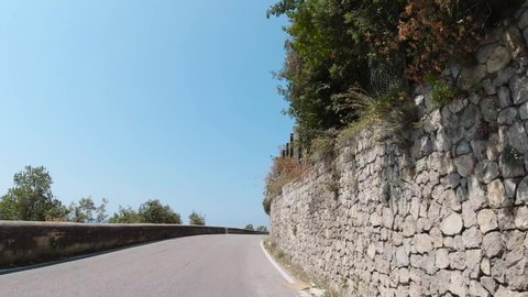 Amalfi, Italy, August 2019: POV dash camera tracking shot front view of driving in the mountainous curvy narrow road of Amalfi coast in Italy