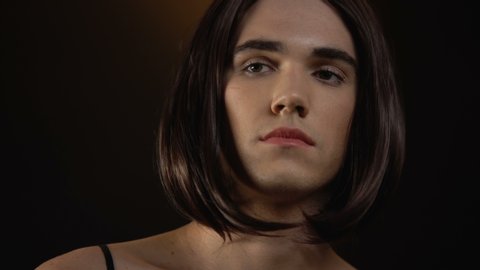 Attractive transgender putting on makeup before cabaret show, gay fashion